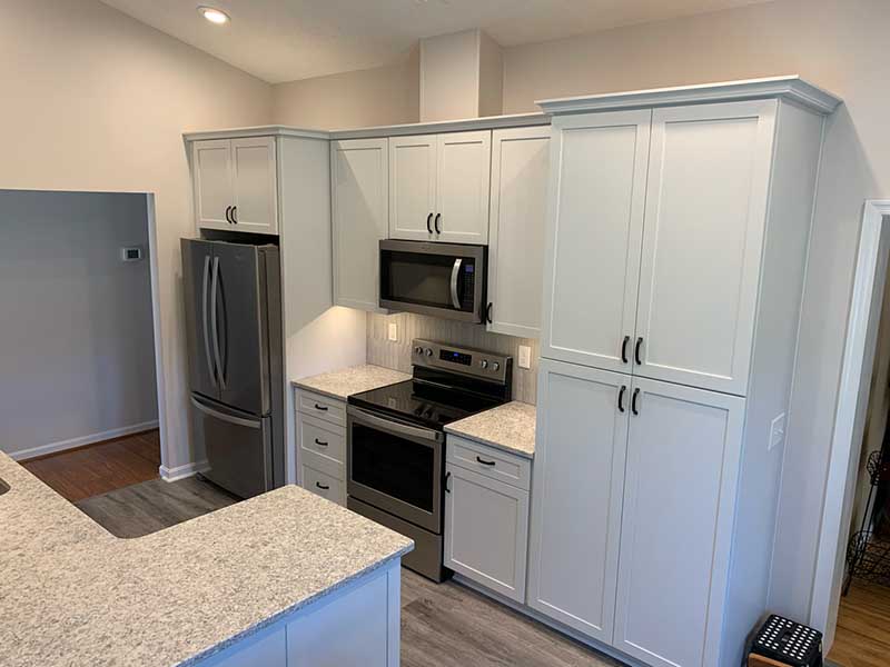 A contemporary kitchen with white cabinets, and a granite countertop.