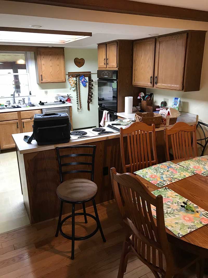An outdated kitchen with faded paint, stained countertops, and mismatched appliances.