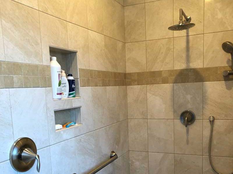 The interior of a brand new, spacious shower with tile floors and walls.