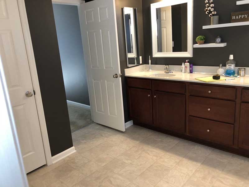 A newly remodeled master bathroom with dark brown, granite-topped cabinetry