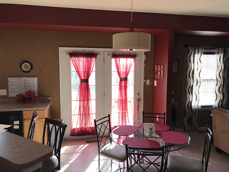An old fashioned dining space with red walls, corian countertops, and a small dining table.