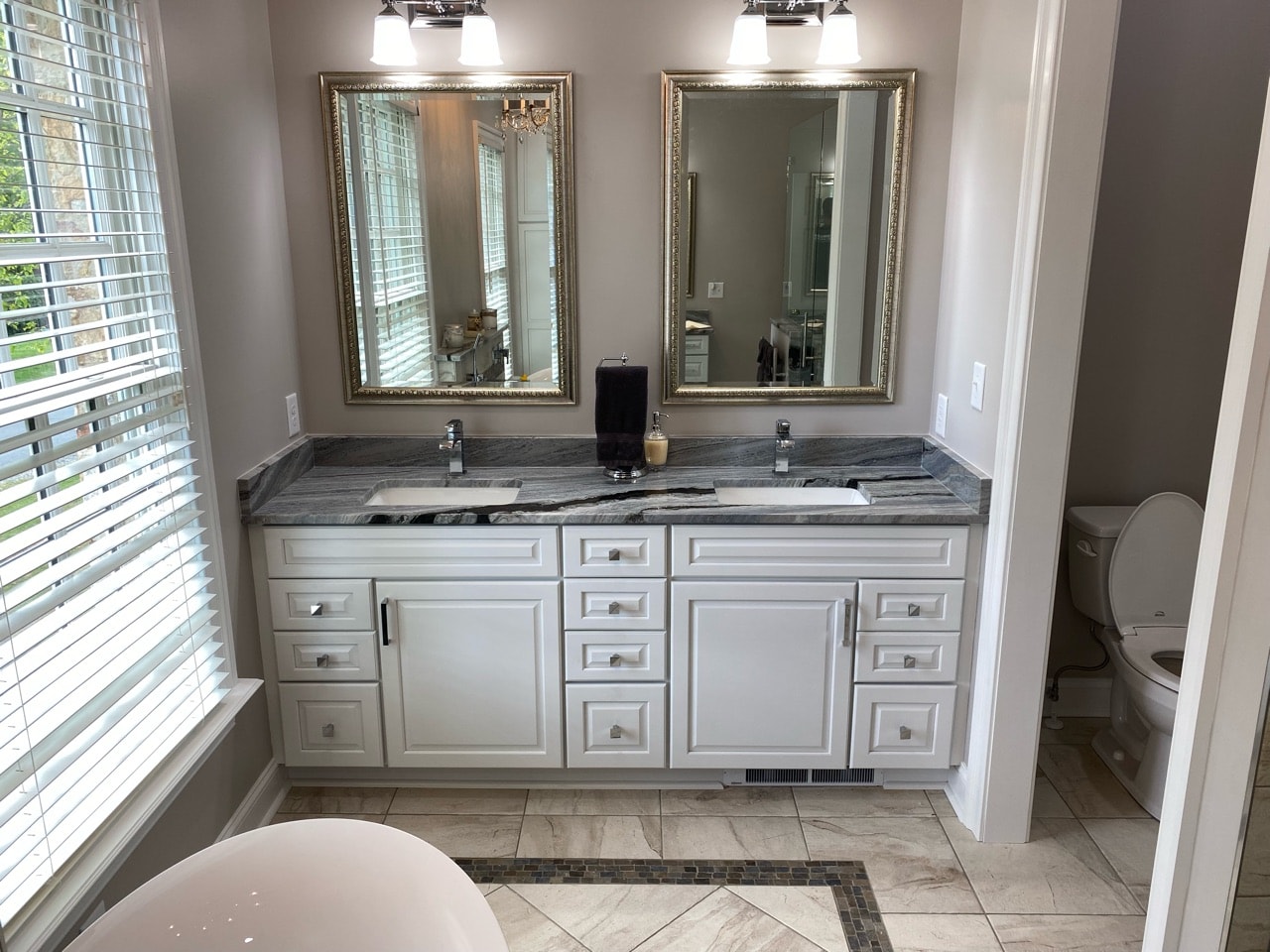 A modern, master bath vanity with large mirrors and overhead lighting