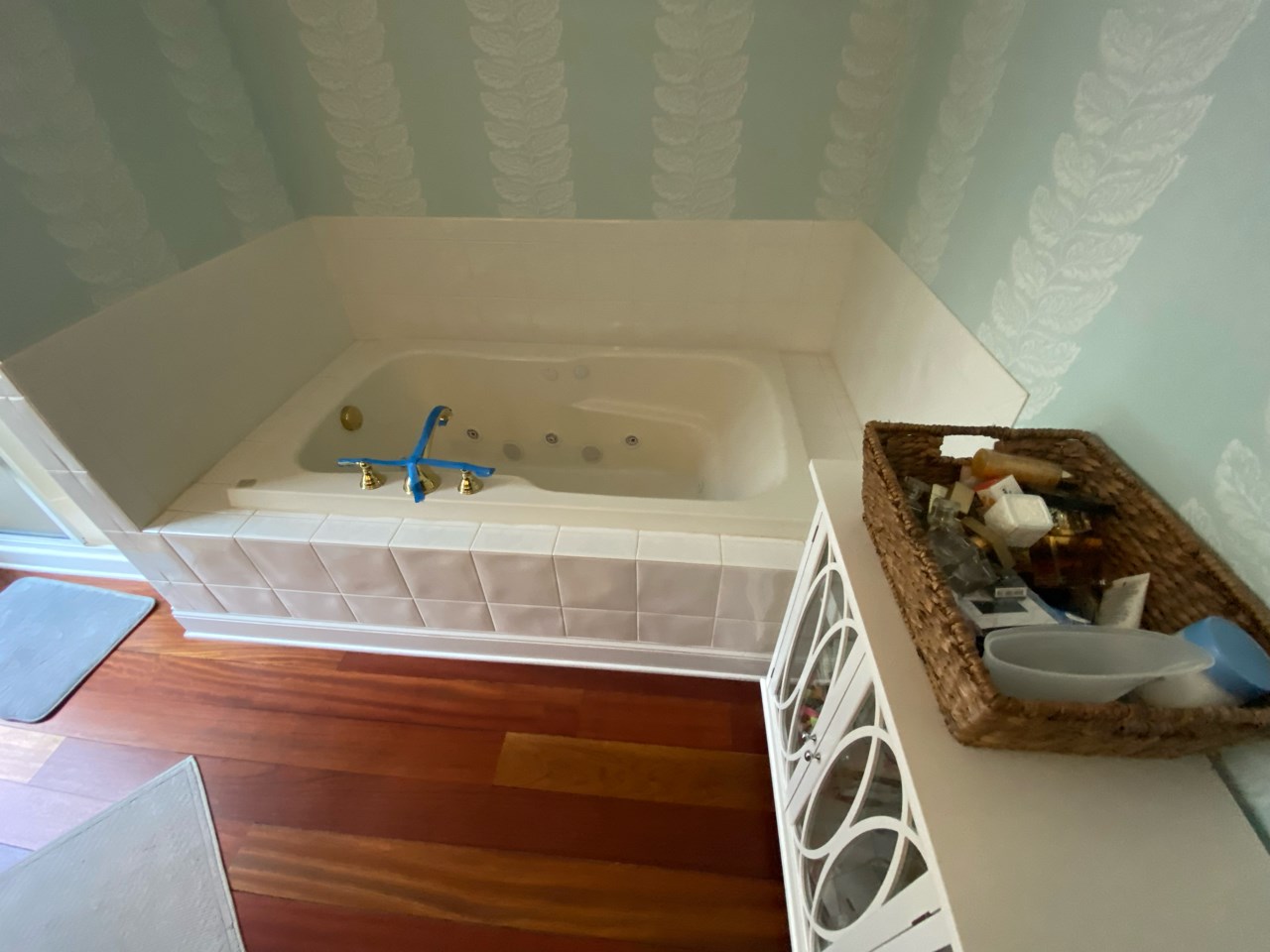 An old bathroom with floral wallpaper and sunken tub.