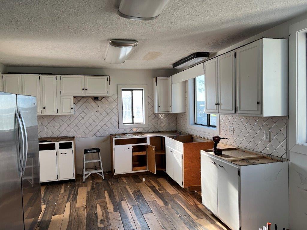 An old, outdated kitchen with brown granite countertops and old cabinetry.