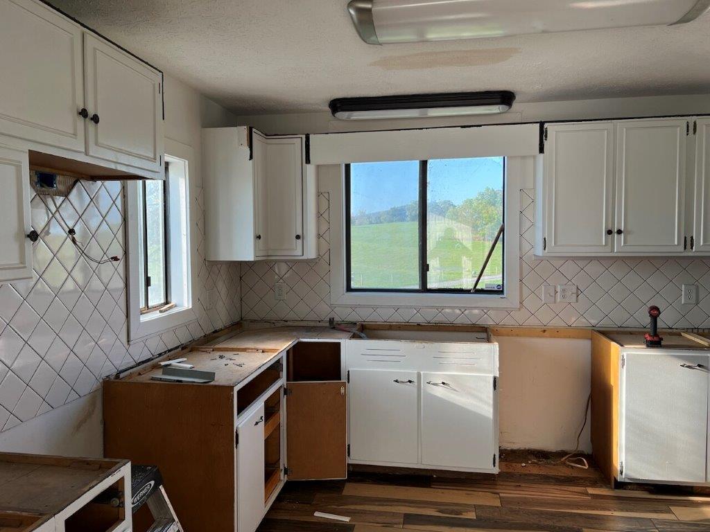 An old kitchen with red walls, worn cabinets, and outdated appliances.