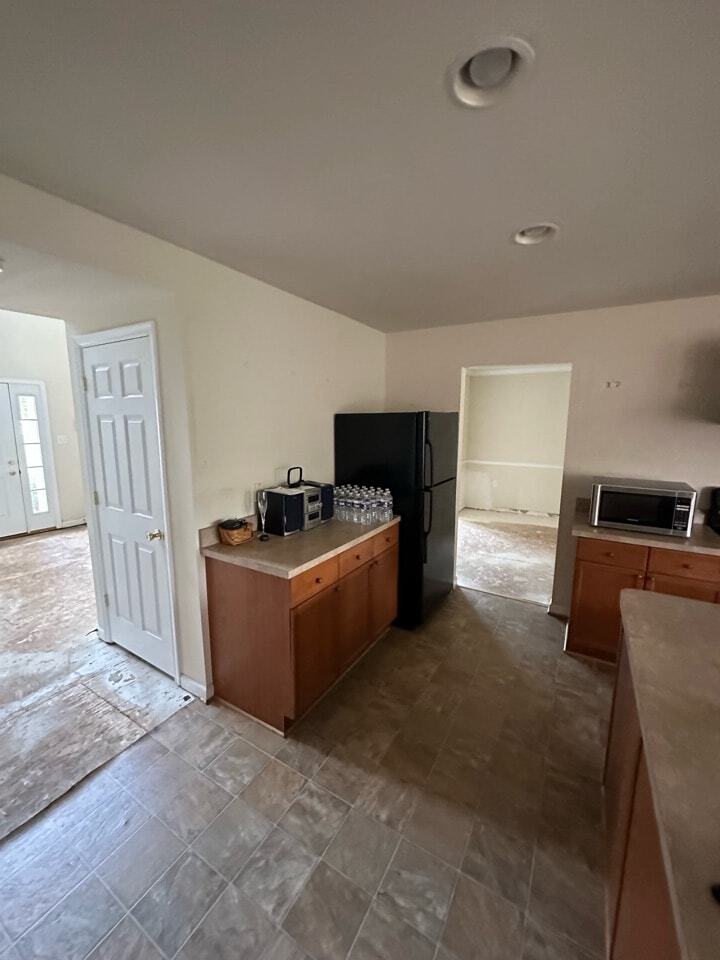 An old, outdated kitchen with brown granite countertops and old cabinetry.