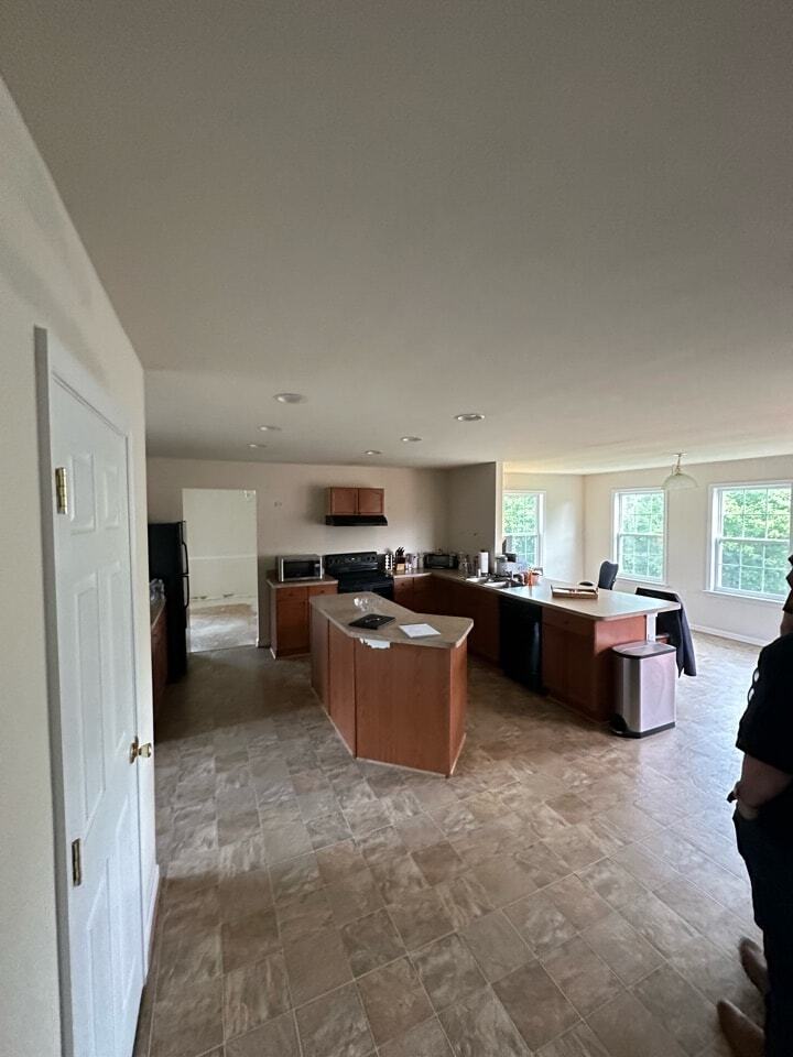 An old, outdated kitchen with brown granite countertops and old cabinetry.