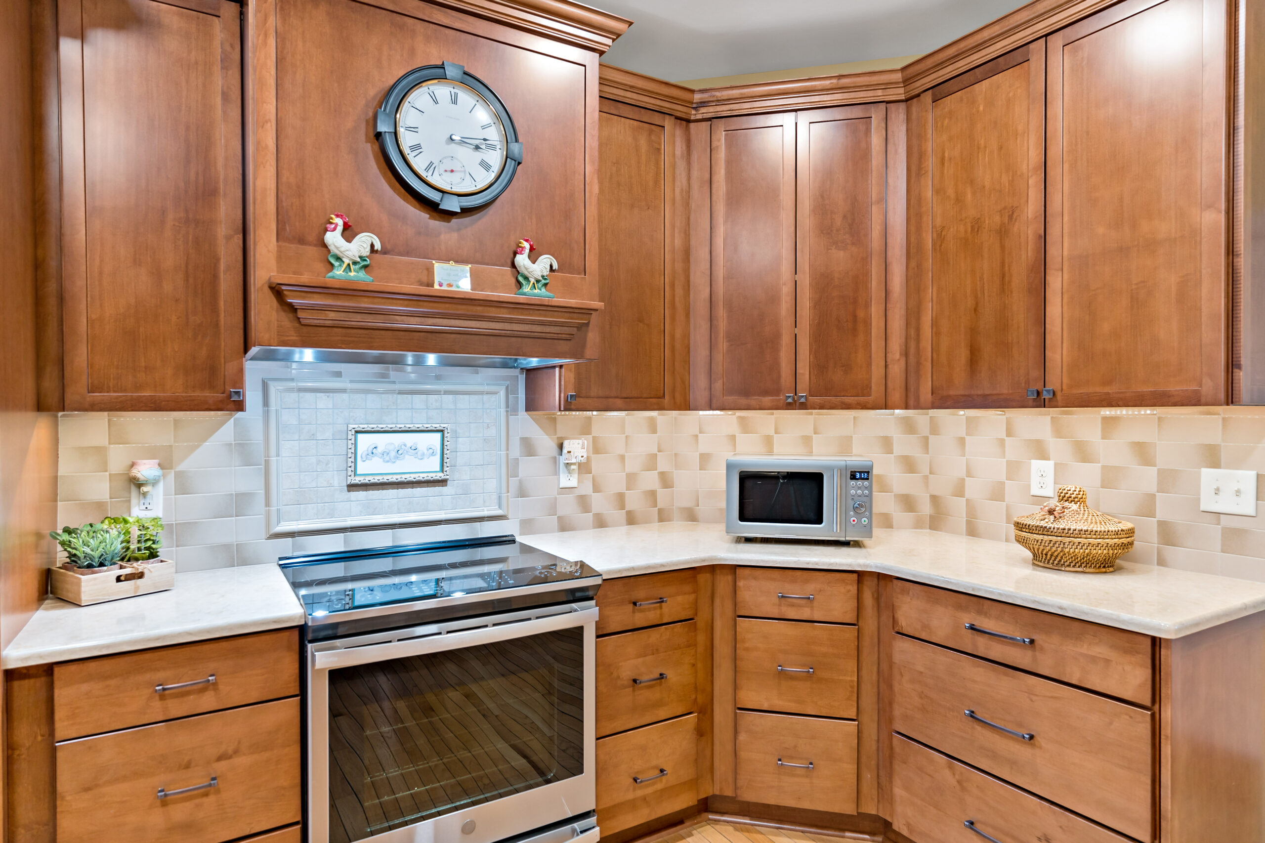 A well-appointed kitchen with warm wood cabinetry, stainless steel appliances, and a decorative tile backsplash in a residential home.