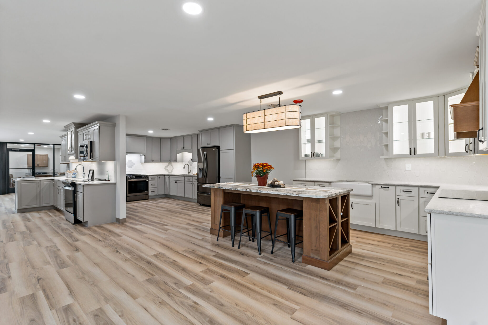 Showroom floor with full kitchen displays, a wood island and pendant lights