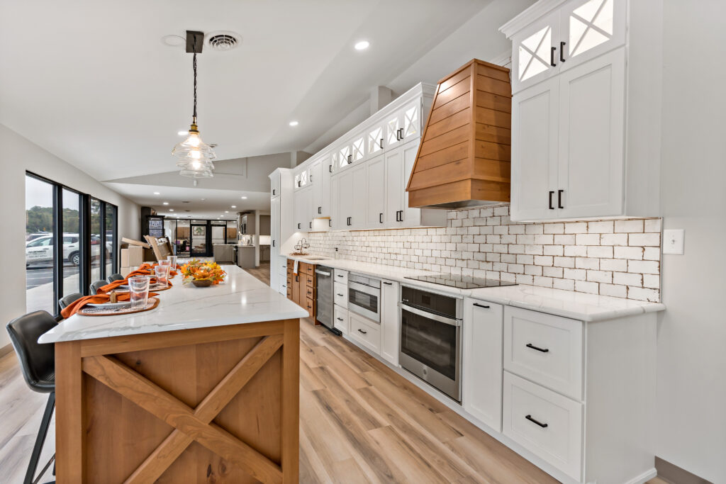 Showroom kitchen with white cabinets, a wood hood and an island