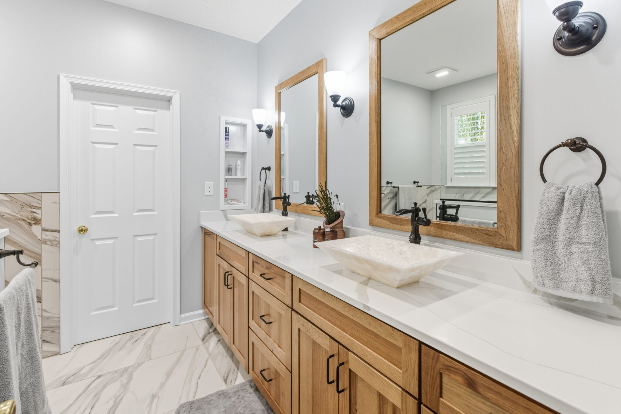 Bathroom with a long wood double vanity, vessel sinks and marble-look tile floors