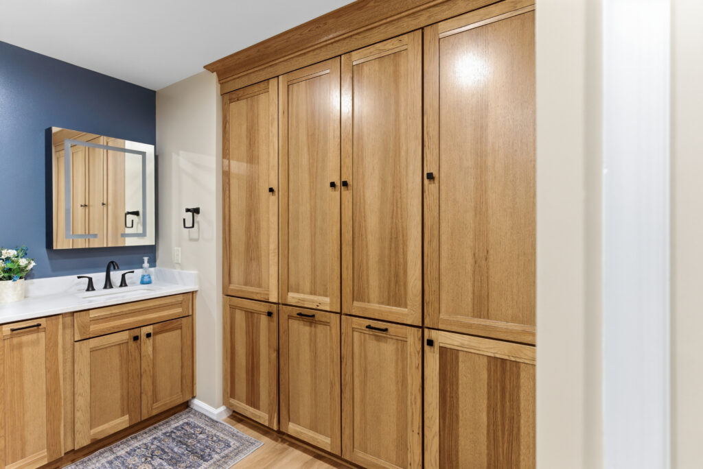 Wood vanity and tall linen cabinet against a navy accent wall