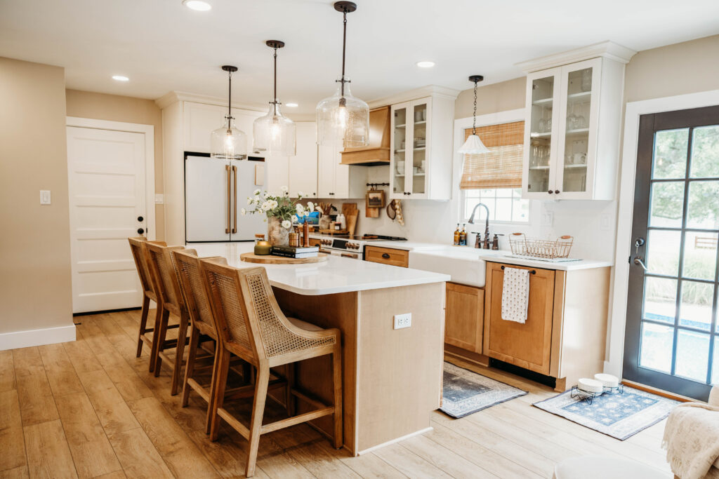 Kitchen with a wood island, woven stools, pendant lights and a farmhouse sink