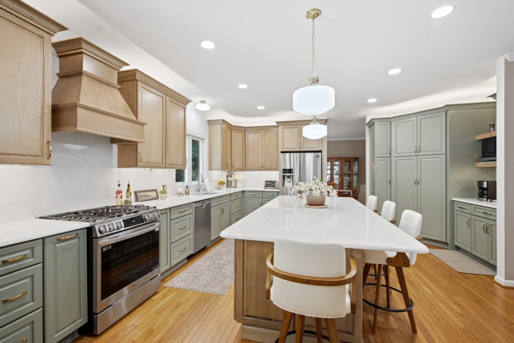 A contemporary kitchen and dining area features natural wood cabinetry, stainless steel appliances, and a round white dining table with modern seating.