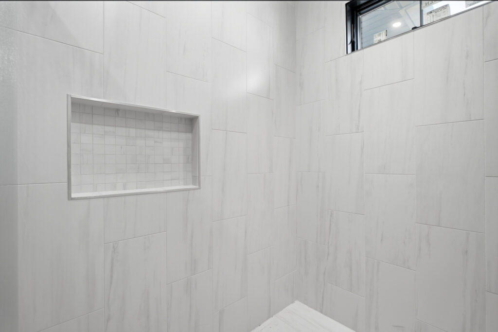 Large curbless tiled shower with a recessed niche and a window